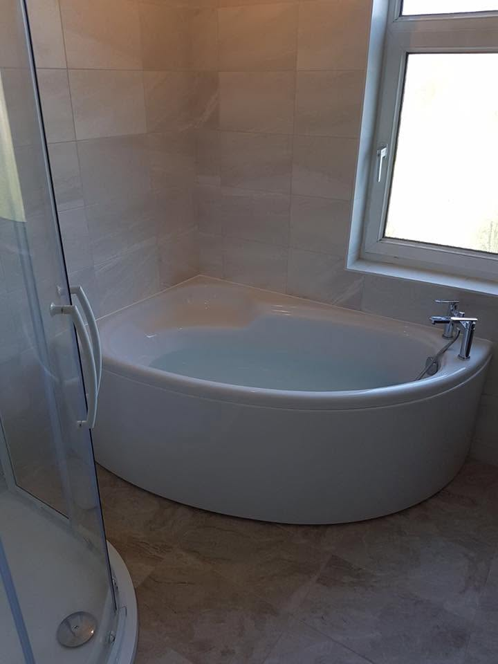 Corner bath installed in a modern tiled bathroom